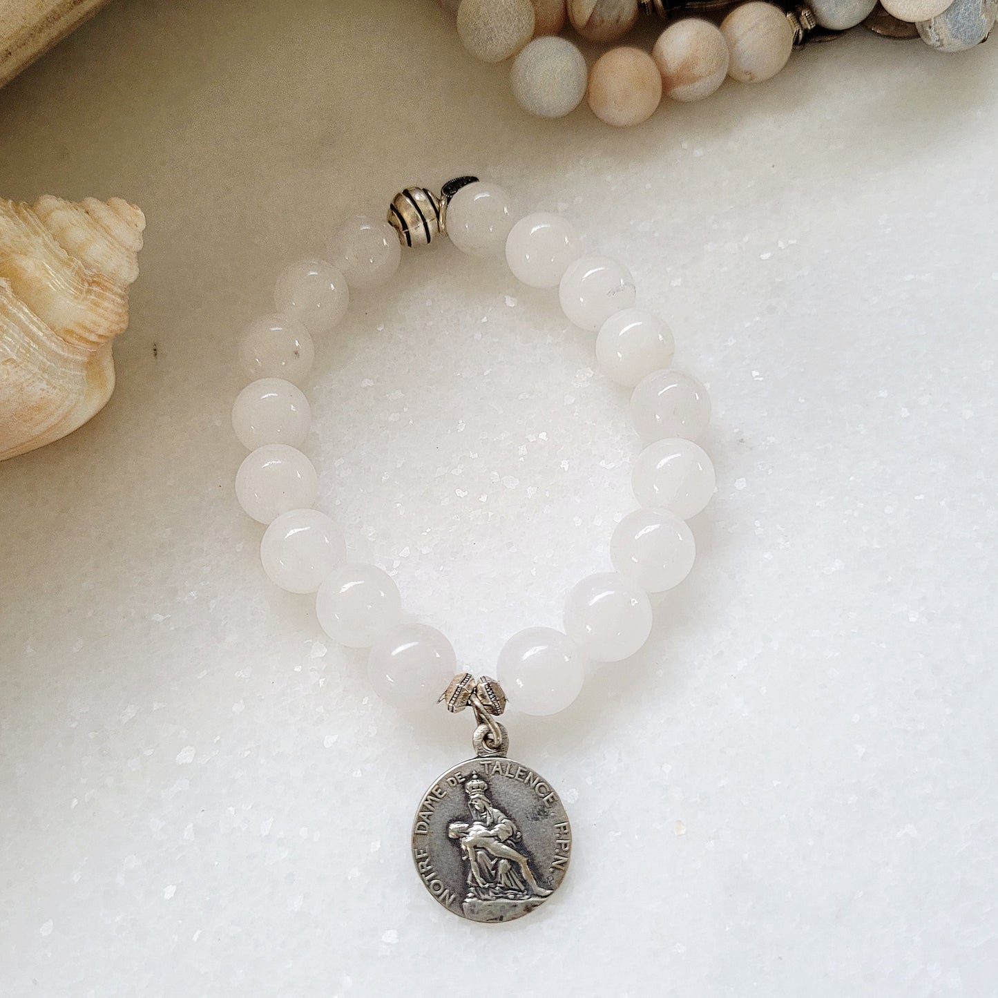 This 10 mm white jade beaded bracelet with silver medal of Our Sorrowful Mother holding Jesus on the front and The Sacred Heart of Jesus on the back.