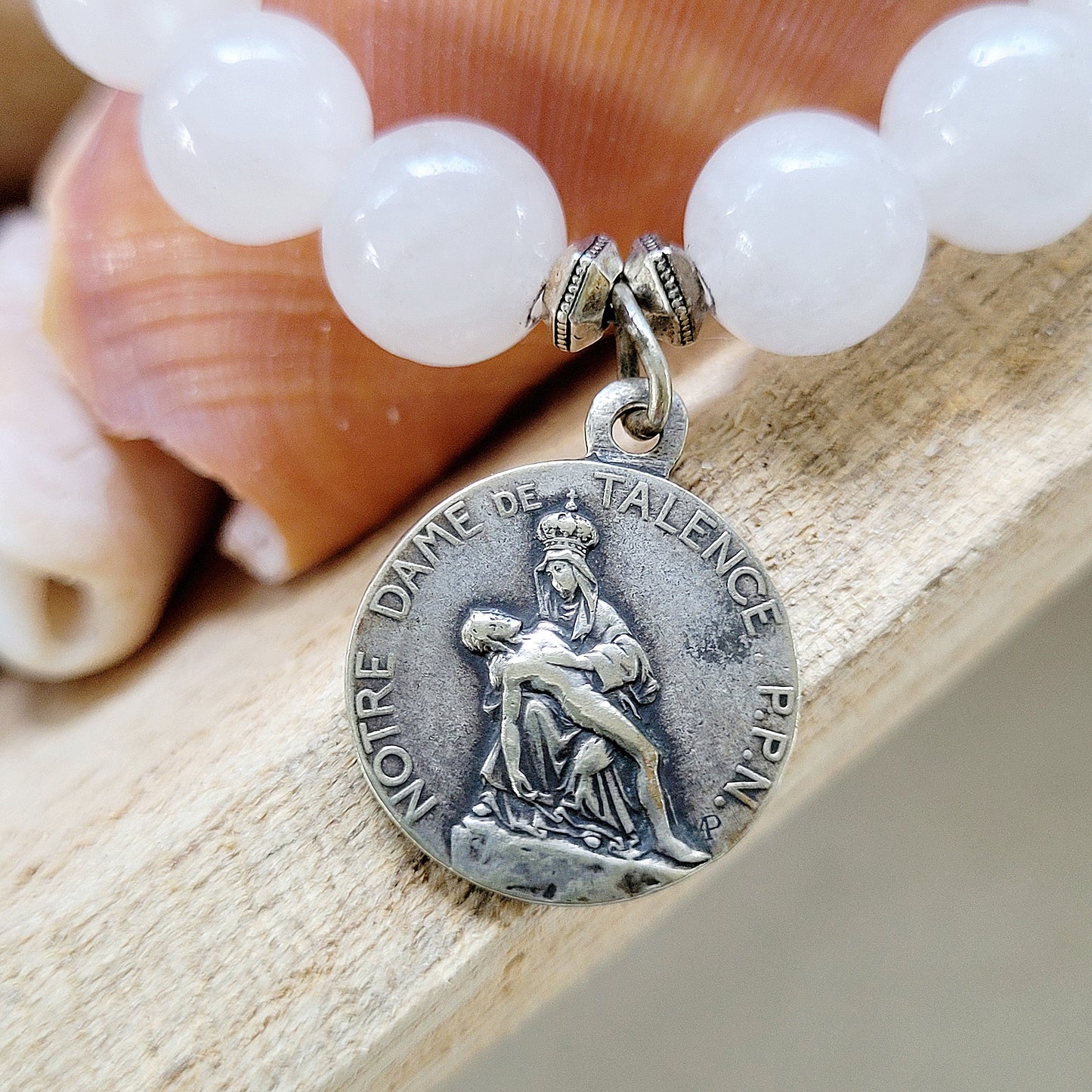 This 10 mm white jade beaded bracelet with silver medal of Our Sorrowful Mother holding Jesus on the front and The Sacred Heart of Jesus on the back.